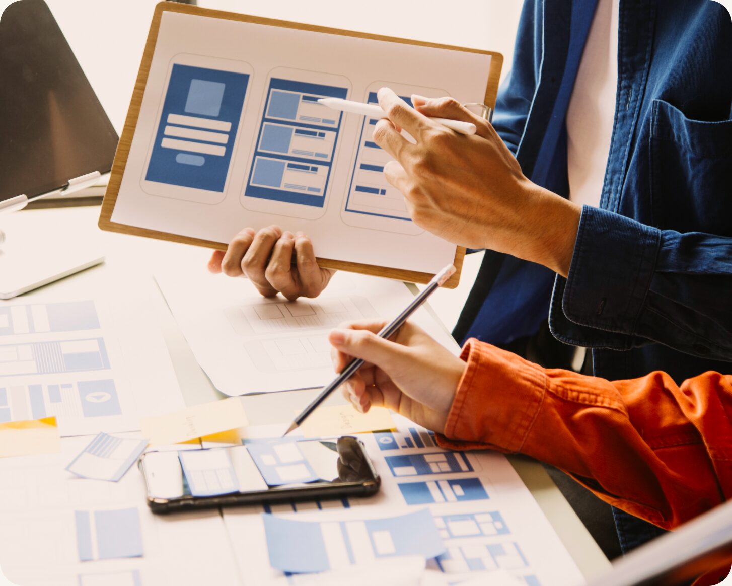 Two designers reviewing printed wireframes at a desk