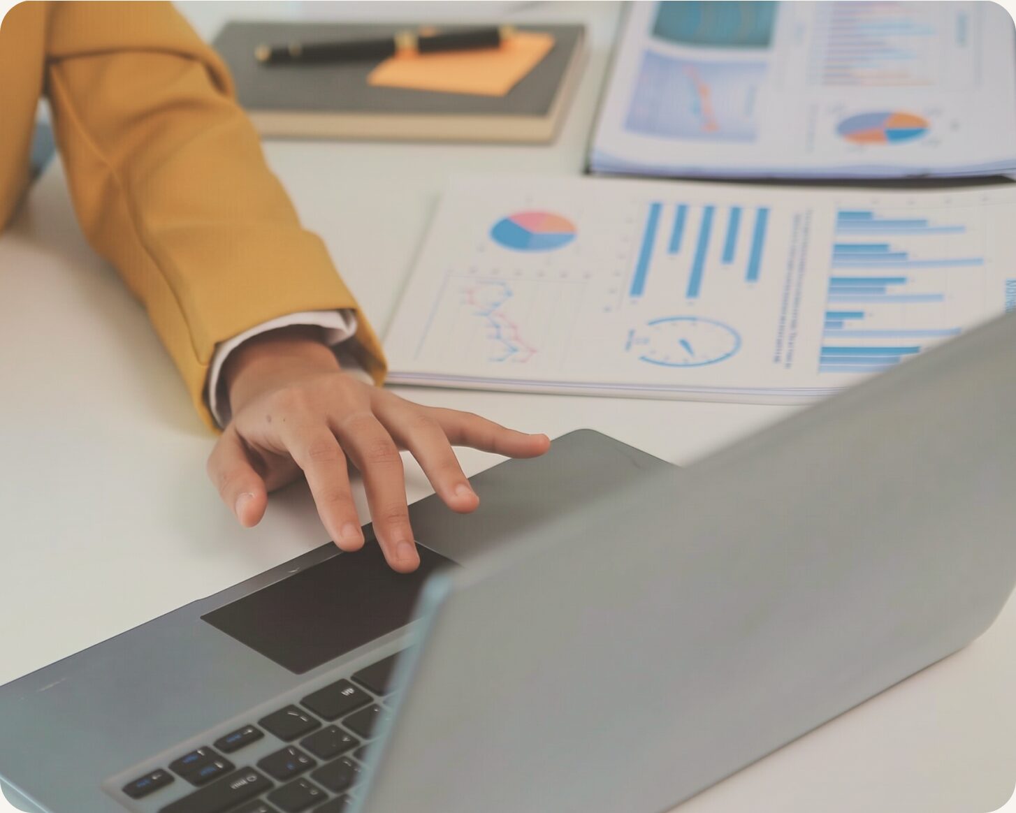 Analyst at a laptop beside printed charts